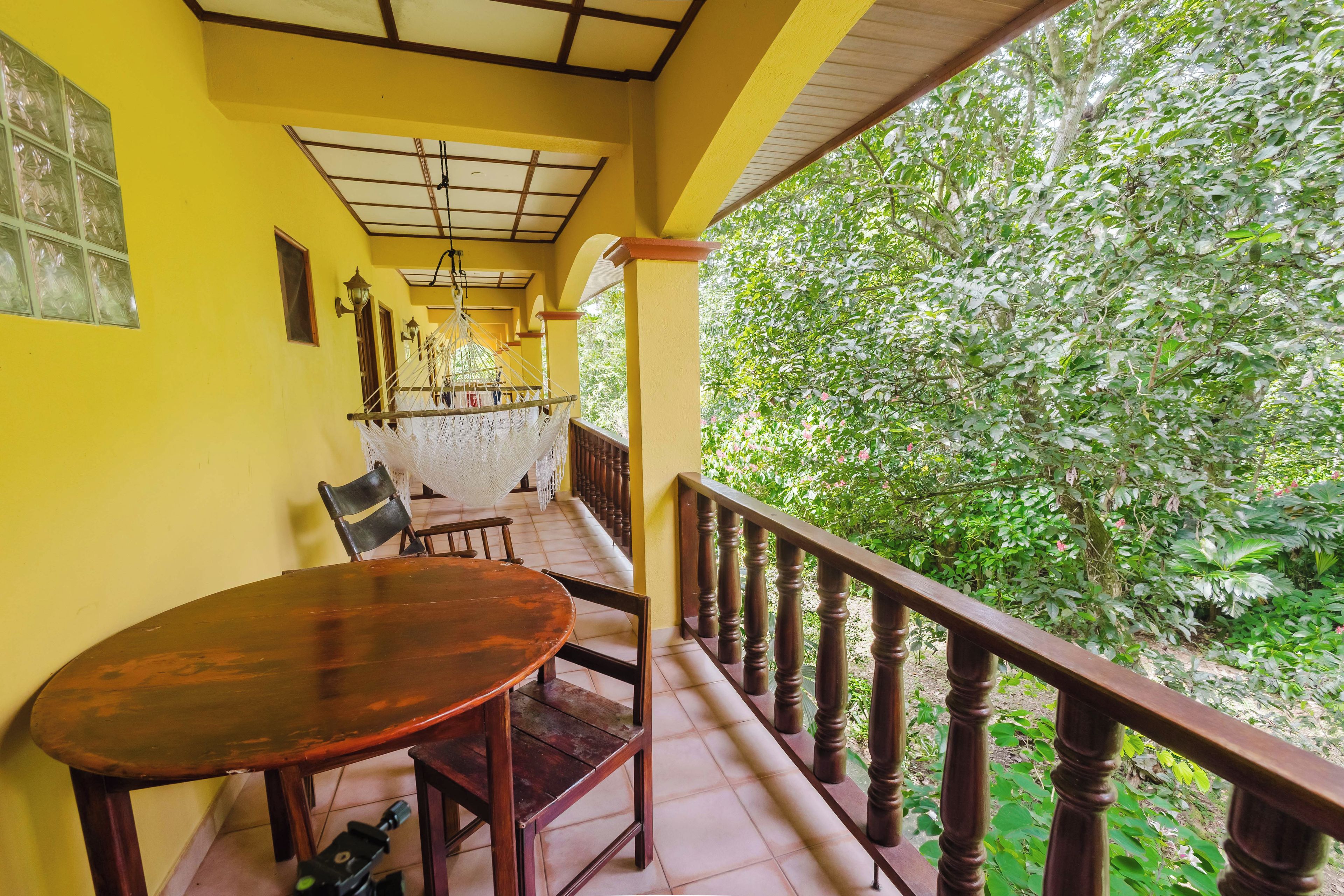 Una mesa y sillas de madera en un balcón con vistas a exuberante vegetación.