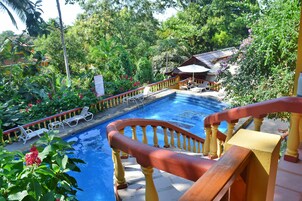 Una piscina al aire libre, sombrillas, sillones reclinables de piscina