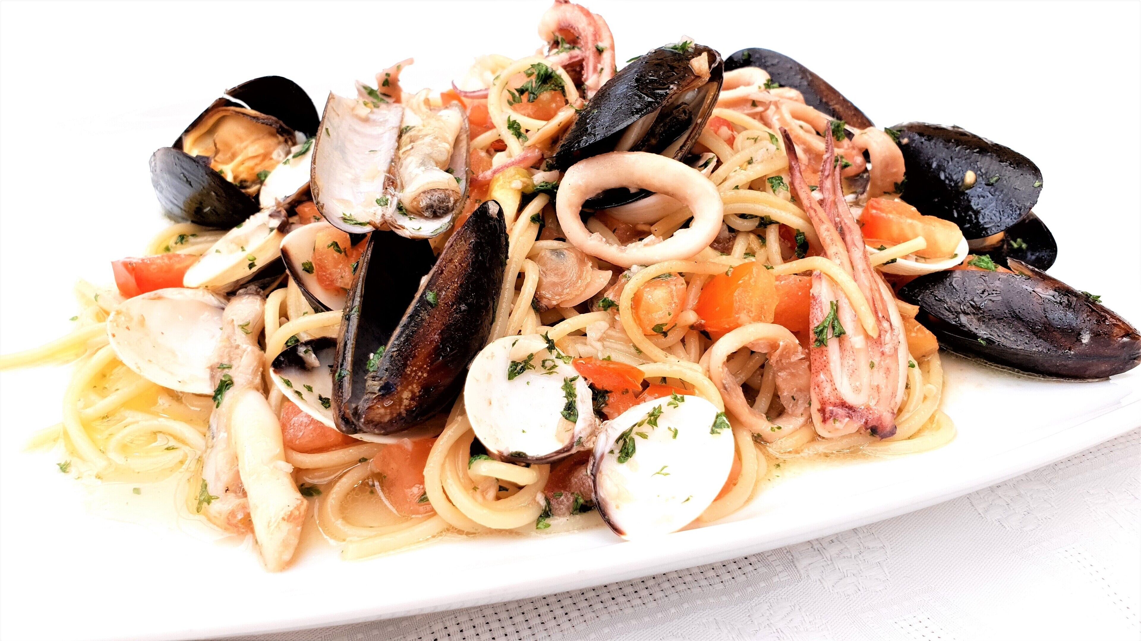 Ein Teller Pasta mit Muscheln und Calamari, garniert mit Kräutern.