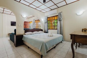 Un dormitorio con cama, escritorio y ventana con cortinas.