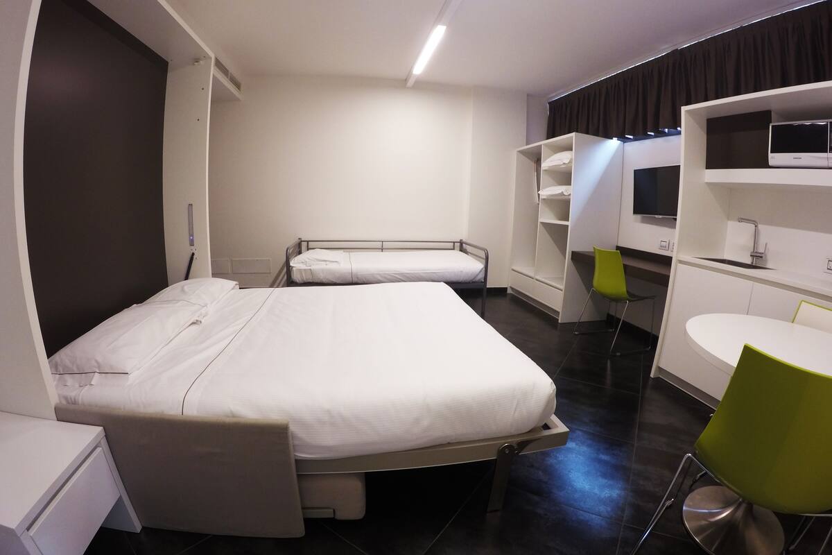 Une chambre d’hôtel moderne équipée d’un grand lit, d’un bureau, d’une chaise, d’une télévision et d’une salle de bain.