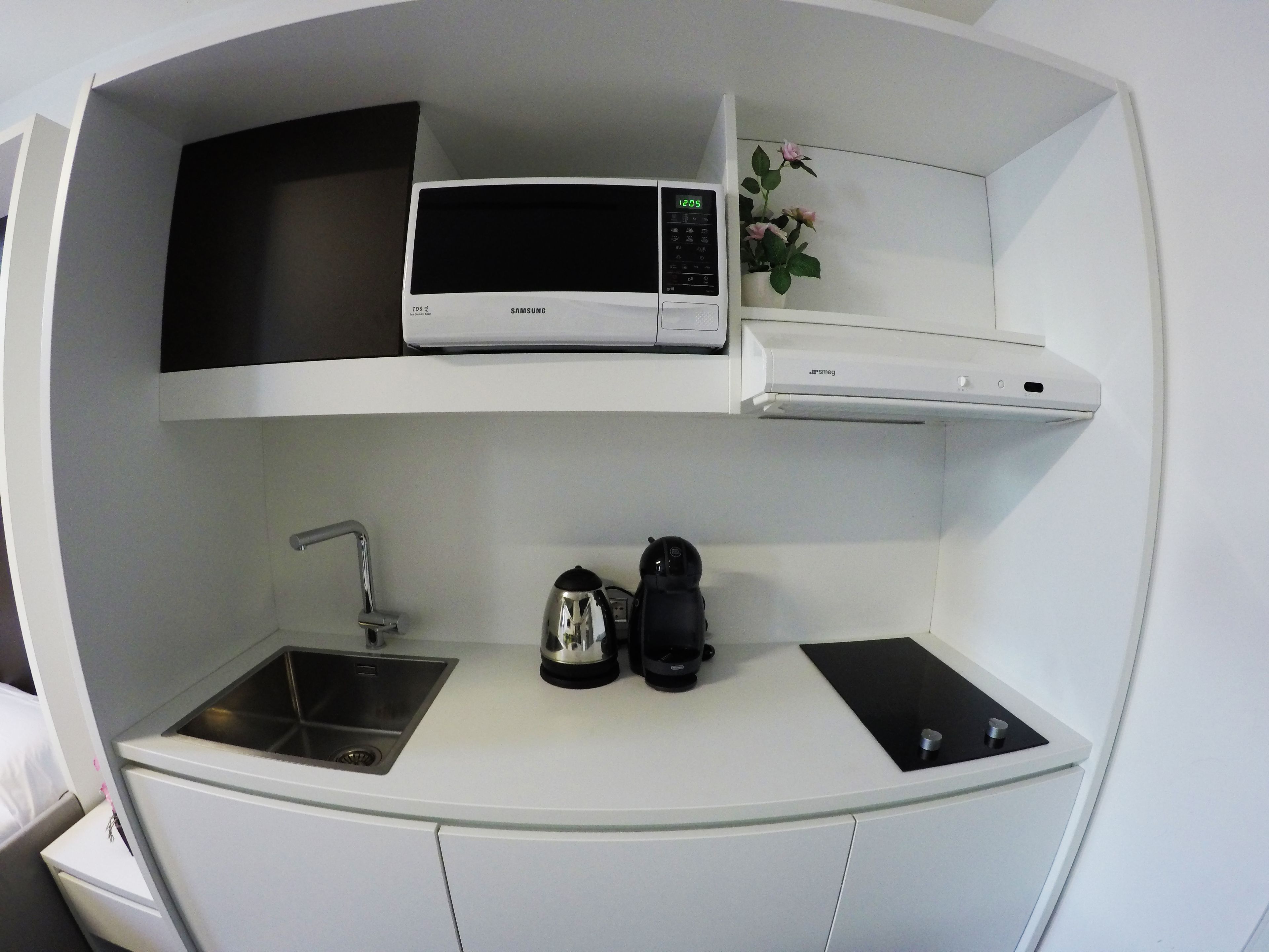 A compact kitchenette with a microwave, a small sink, and a coffee maker.