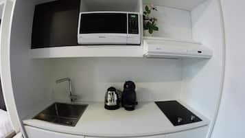 A compact kitchenette with a microwave, a small sink, and a coffee maker.