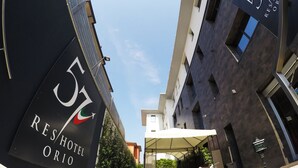 Una entrada de hotel moderna con un área de estar al aire libre techada y una vista despejada del cielo.