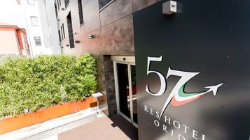A modern hotel entrance with a large sign displaying the number 57 and the name "RENHOTEL ORIO".