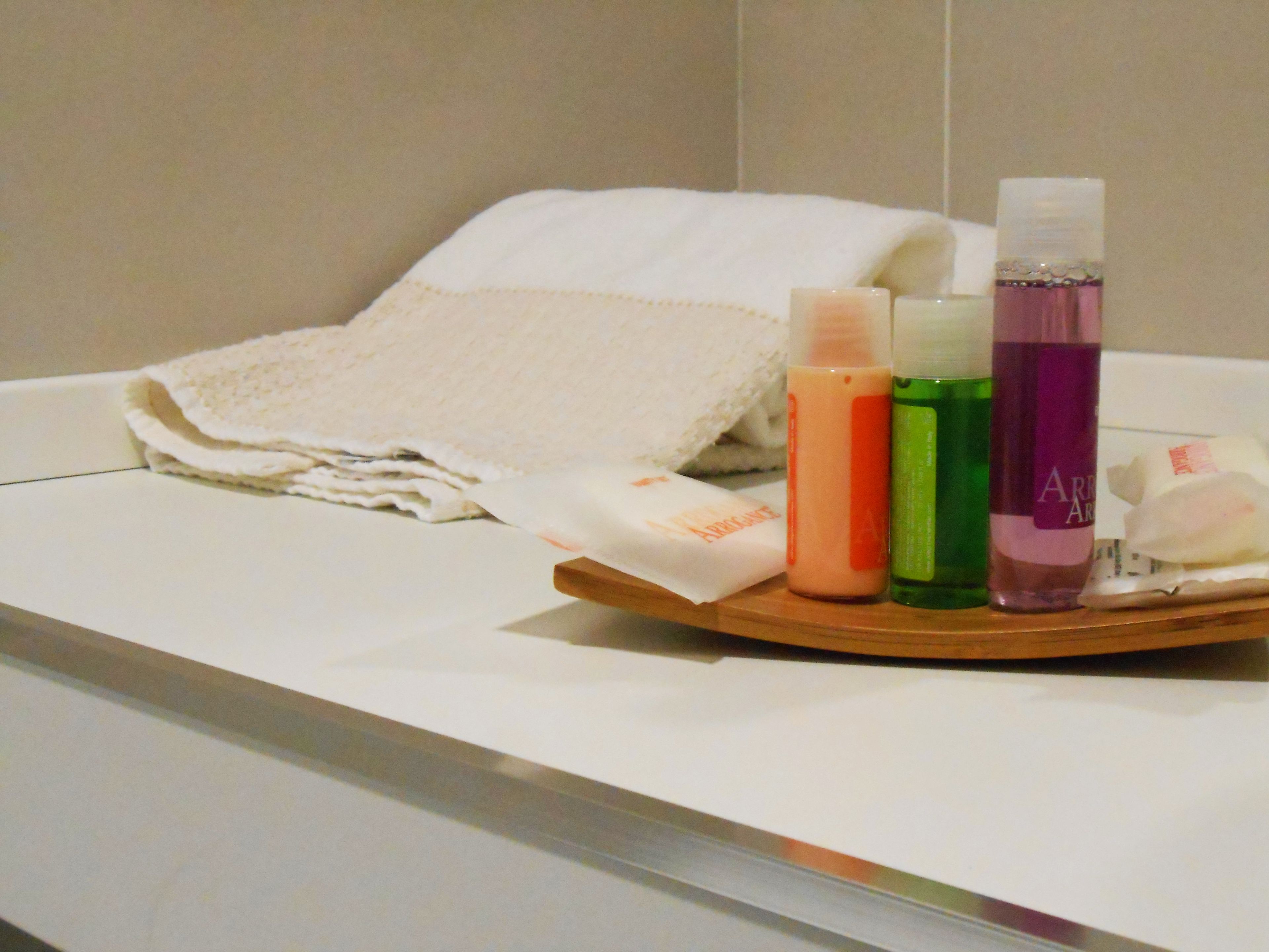 Une chambre d’hôtel avec un lit soigneusement fait, un plateau avec des articles de toilette et une serviette blanche.