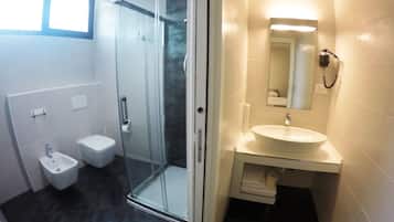 Une salle de bain moderne avec une douche à parois de verre, des toilettes et un lavabo avec un miroir.