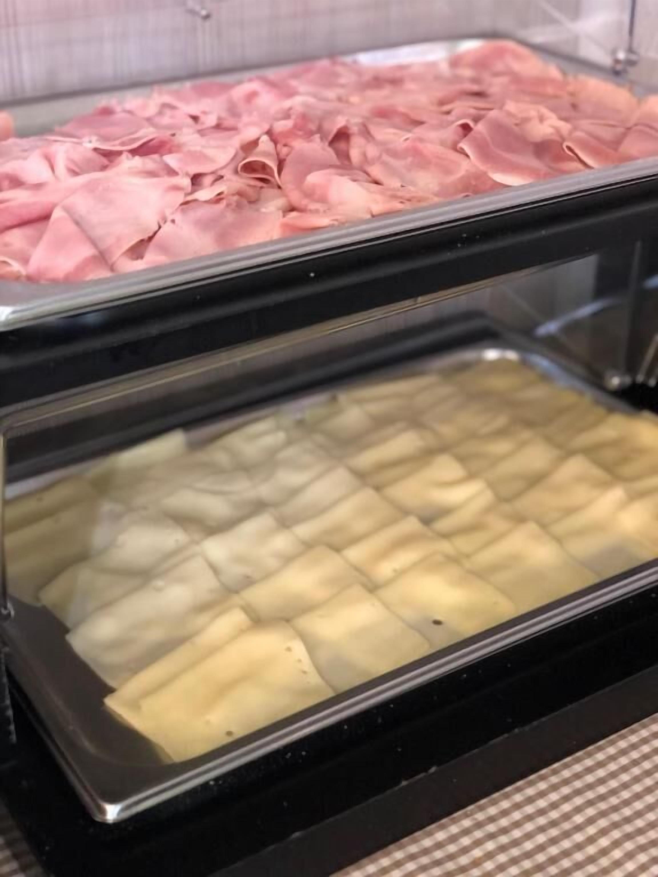 Un bufé con bandejas de carnes y quesos en porciones.
