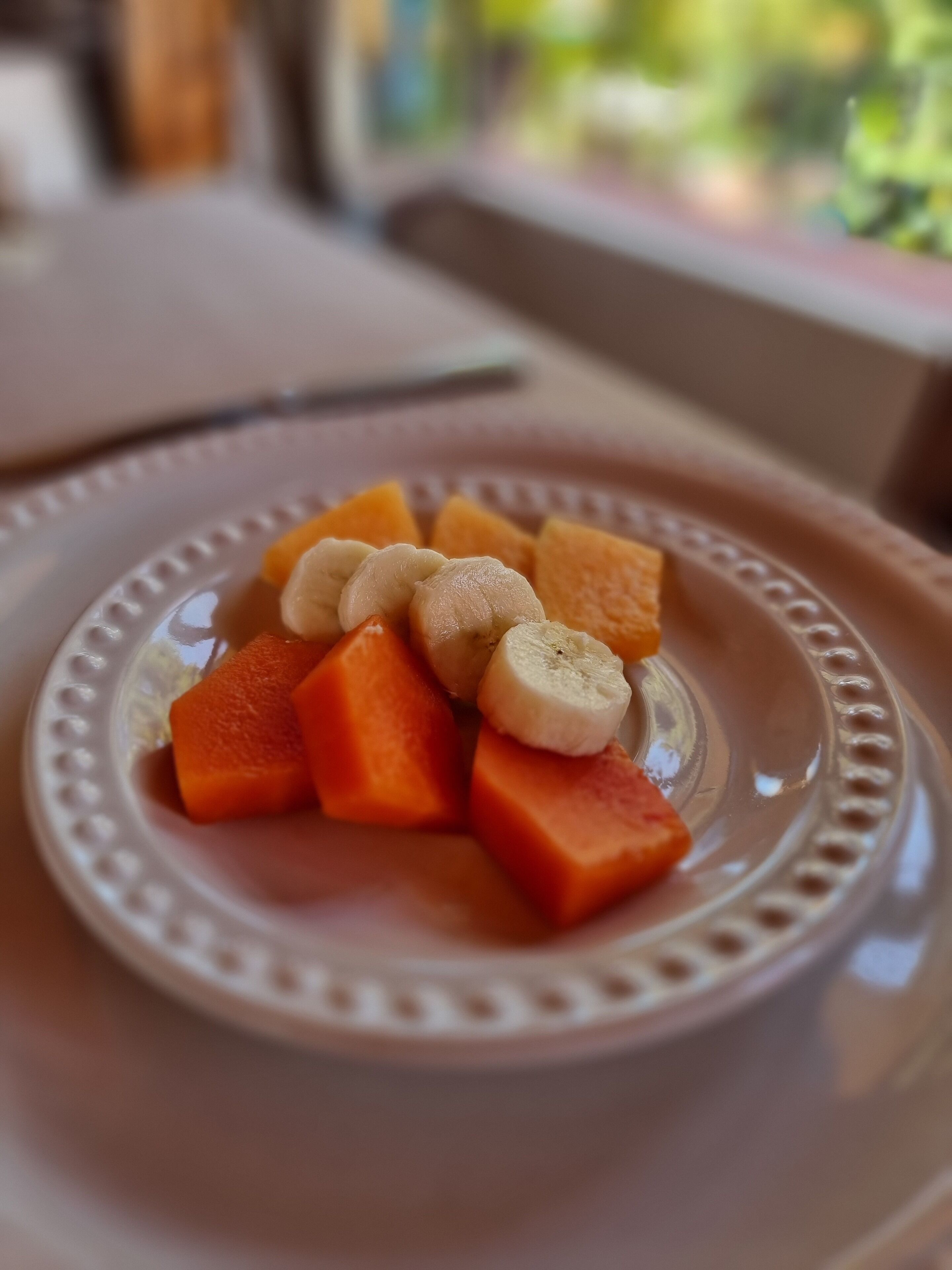 A plate with sliced fruits on a table.