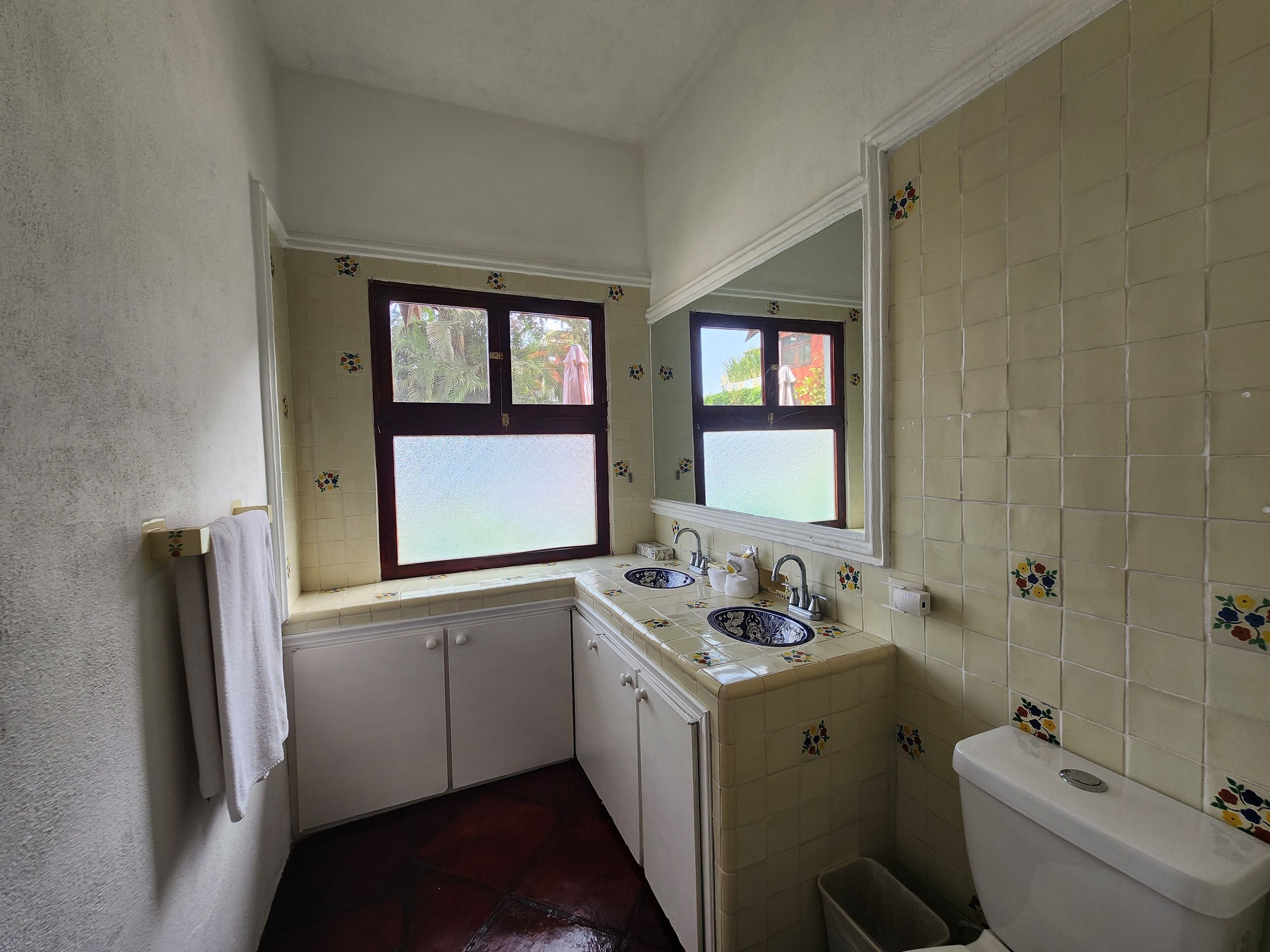 Une petite salle de bain avec une fenêtre, un lavabo, des toilettes et un meuble de rangement.