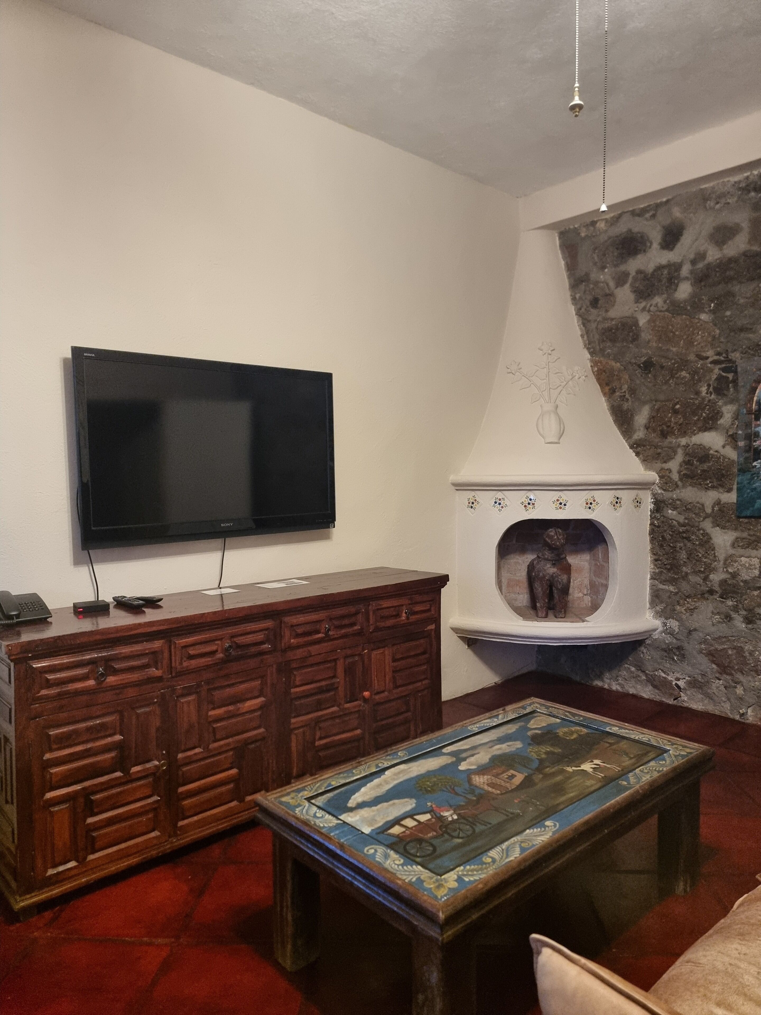 Ein Wohnzimmer mit Flachbildfernseher, Holzschrank, Steinwand und gefliestem Couchtisch.