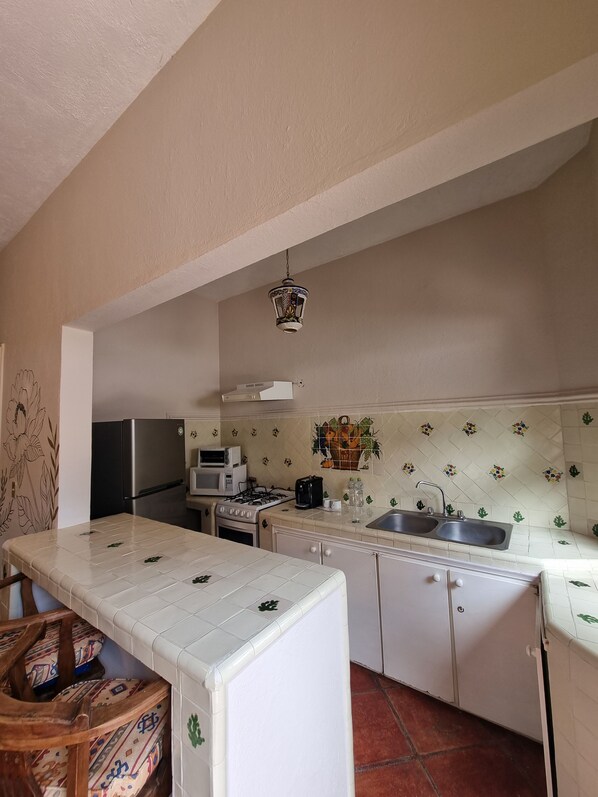 Una cocina compacta equipada con refrigerador, microondas, estufa y lavadero.