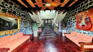 A spacious interior with a stone wall, a wooden ceiling, and a staircase leading to an upper level. - Hacienda de las Flores (San Miguel de Allende)