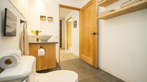 A bathroom with a toilet, sink, and wooden door. - Las Avellanas Villas (Tamarindo)