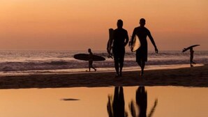 A beach scene with people walking and carrying surfboards. - Las Avellanas Villas (Tamarindo)