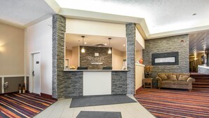 A reception area with a stone accent wall, a reception desk, and a sofa in the background. - Quality Hotel Drumheller (Drumheller)