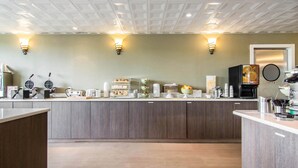 A modern kitchen with wooden cabinets, a countertop with various appliances, and wall-mounted light fixtures. - Quality Hotel Drumheller (Drumheller)