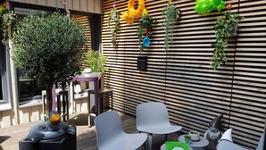 A modern outdoor seating area with a wooden slatted wall, potted plants, and a small garden feature. - Campanile Nancy Centre - Gare (Nancy)