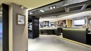 A modern interior with a reception area, a counter, and a display of products. - Campanile Nancy Centre - Gare (Nancy)