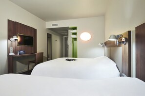 A hotel room with a bed, a desk with a flat-screen TV, a chair, and a green door leading to a bathroom. - Campanile Nancy Centre - Gare (Nancy)