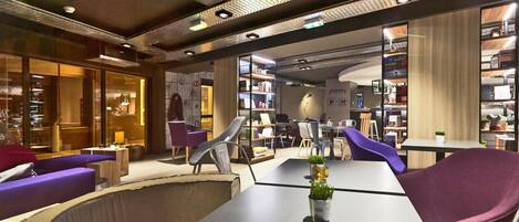 Una biblioteca moderna con estanterías, asientos cómodos y una mesa central con una planta.
