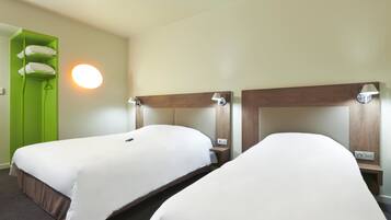 A hotel room with two single beds, a green wardrobe, and a round wall light.