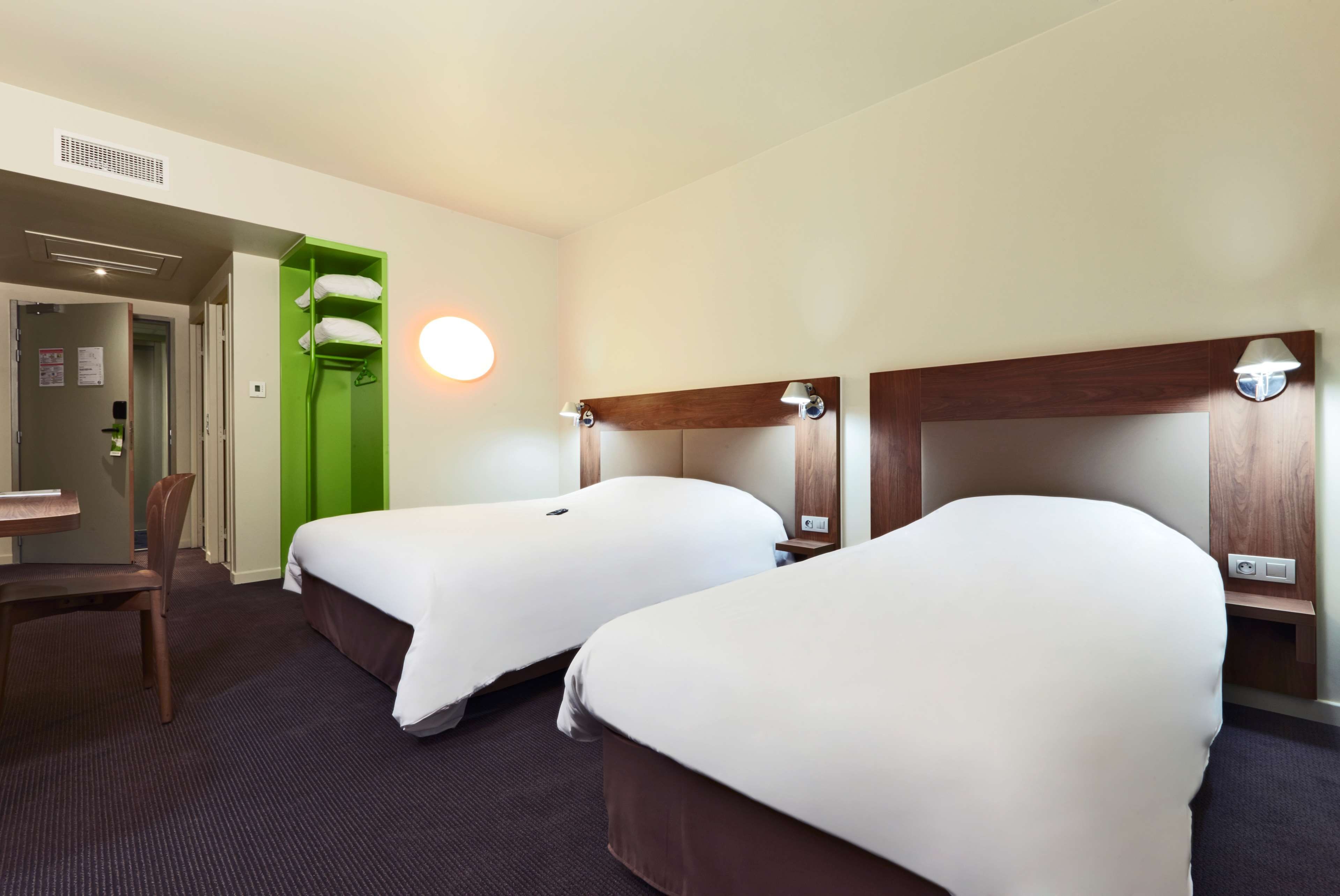 Une chambre d’hôtel avec deux lits, un bureau et une chaise.