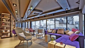 A modern interior with a purple sofa, wooden coffee table, and a bookshelf. - Campanile Nancy Centre - Gare (Nancy)