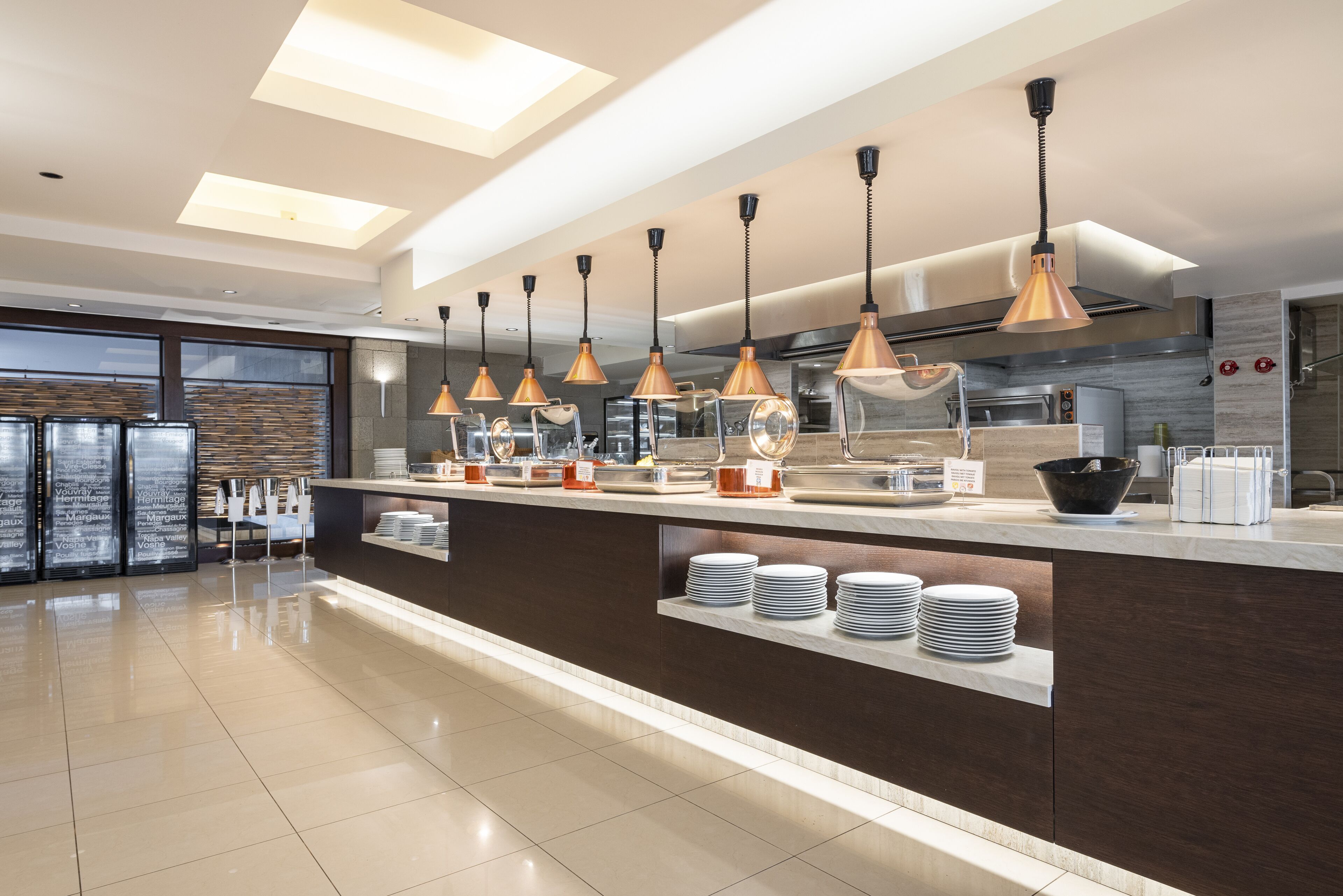A modern kitchen with a central island, pendant lighting, and a view of the dining area.