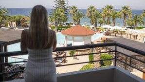 A balcony with a view of a beach, palm trees, and a pool area. - D'Andrea Mare Beach Hotel – All Inclusive (Rhodes)