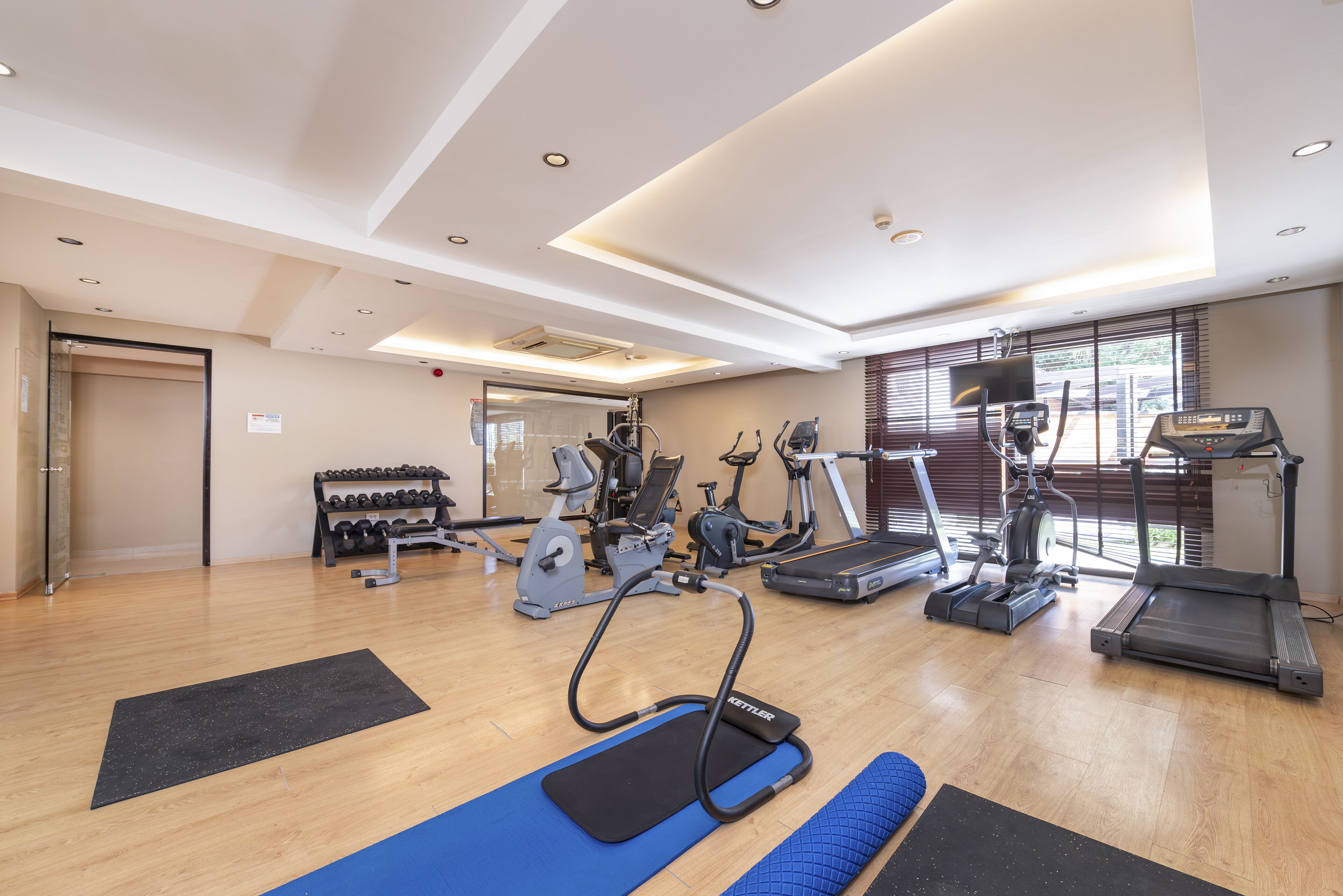 A gym with various exercise equipment, including treadmills, stationary bikes, and dumbbells.