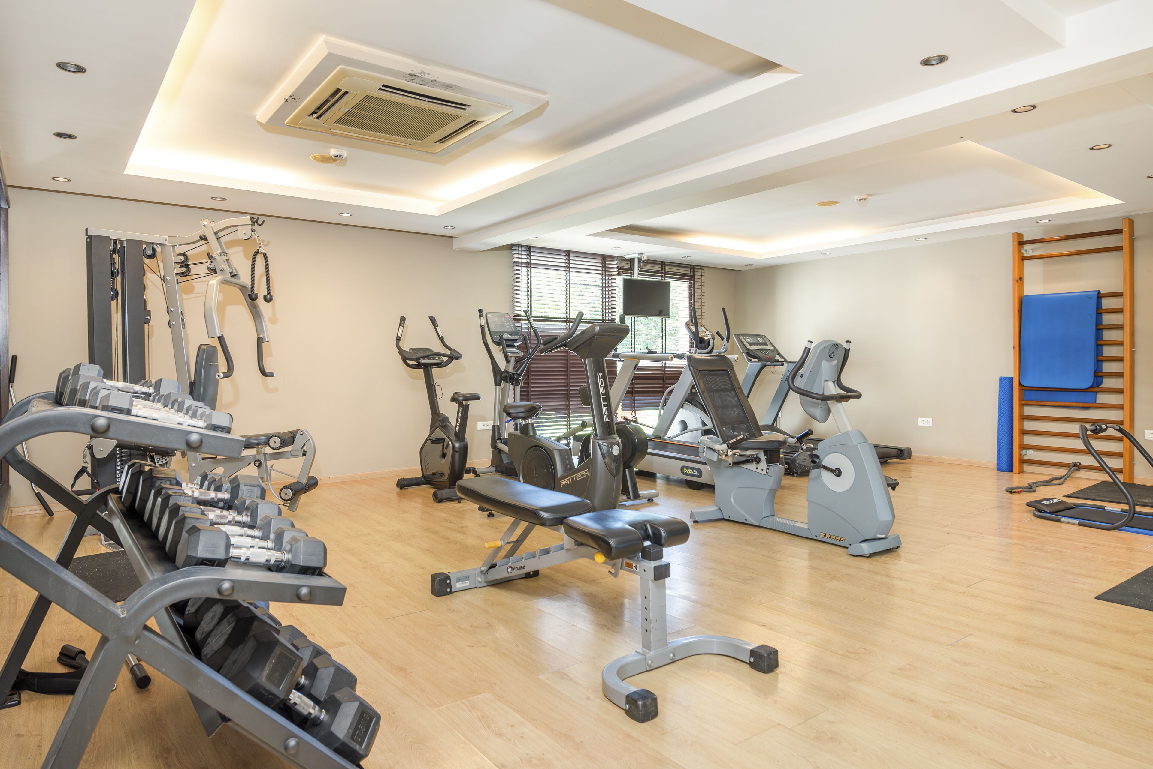 A gym with various exercise equipment including treadmills, elliptical machines, and weight benches.