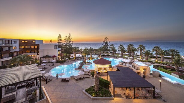 A resort with a swimming pool, lounge areas, and a view of the ocean at sunset. - D'Andrea Mare Beach Hotel – All Inclusive (Rhodes)