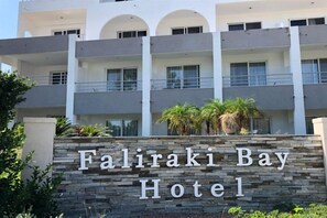 A multi-story hotel with a stone facade and balconies. - Faliraki Bay (Rhodes)