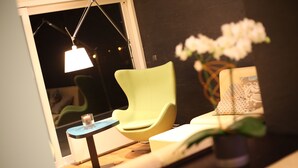 A modern room with a green chair, a small table with a candle, and a potted plant.