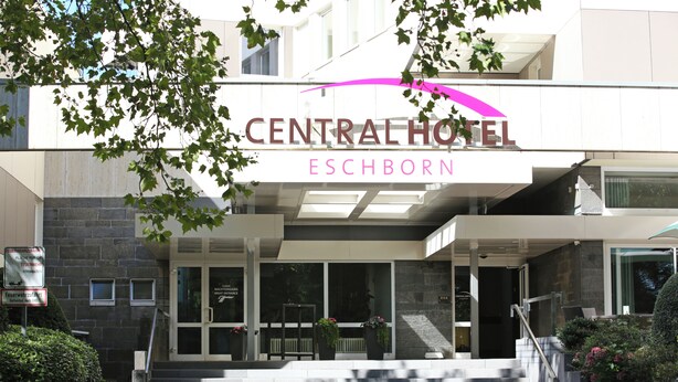 A hotel entrance with a sign reading "CENTRAL HOTEL ESCHBORN".