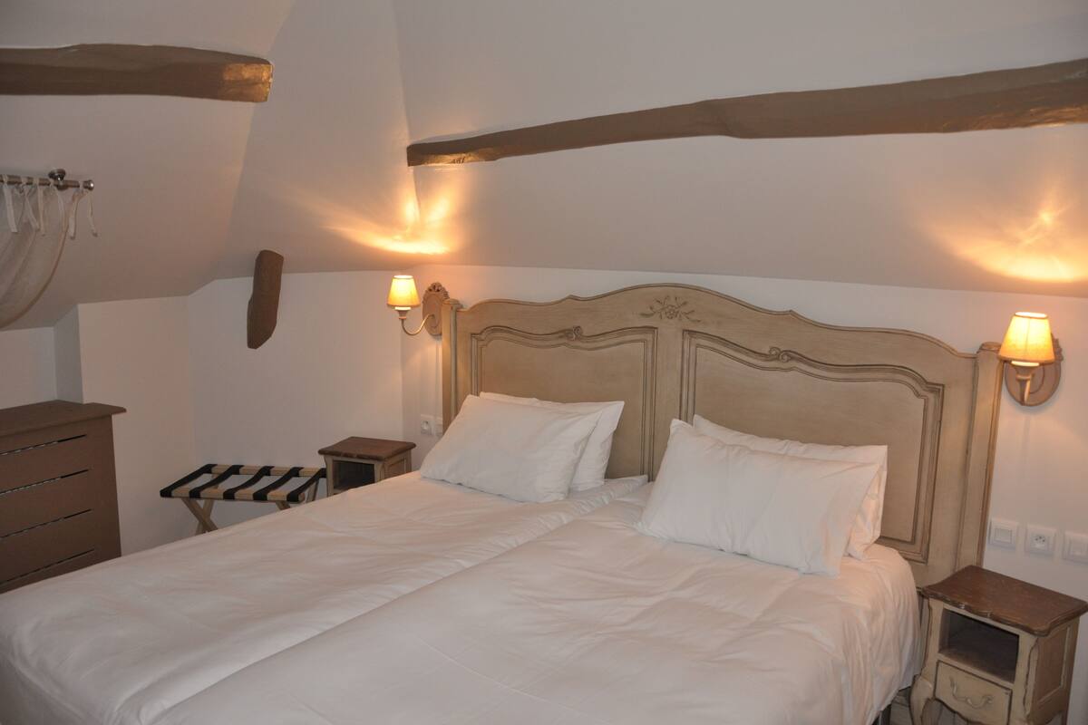 A bedroom with a large bed, two bedside tables, a wooden dresser, and wall-mounted lamps.