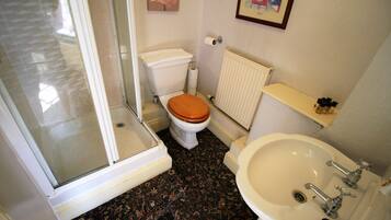 Een badkamer met toilet, douche, wastafel en radiator.