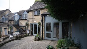 A stone building with a patio area, outdoor seating, and a staircase leading to an upper level. - The Kings Arms Chipping Norton (Chipping Norton)