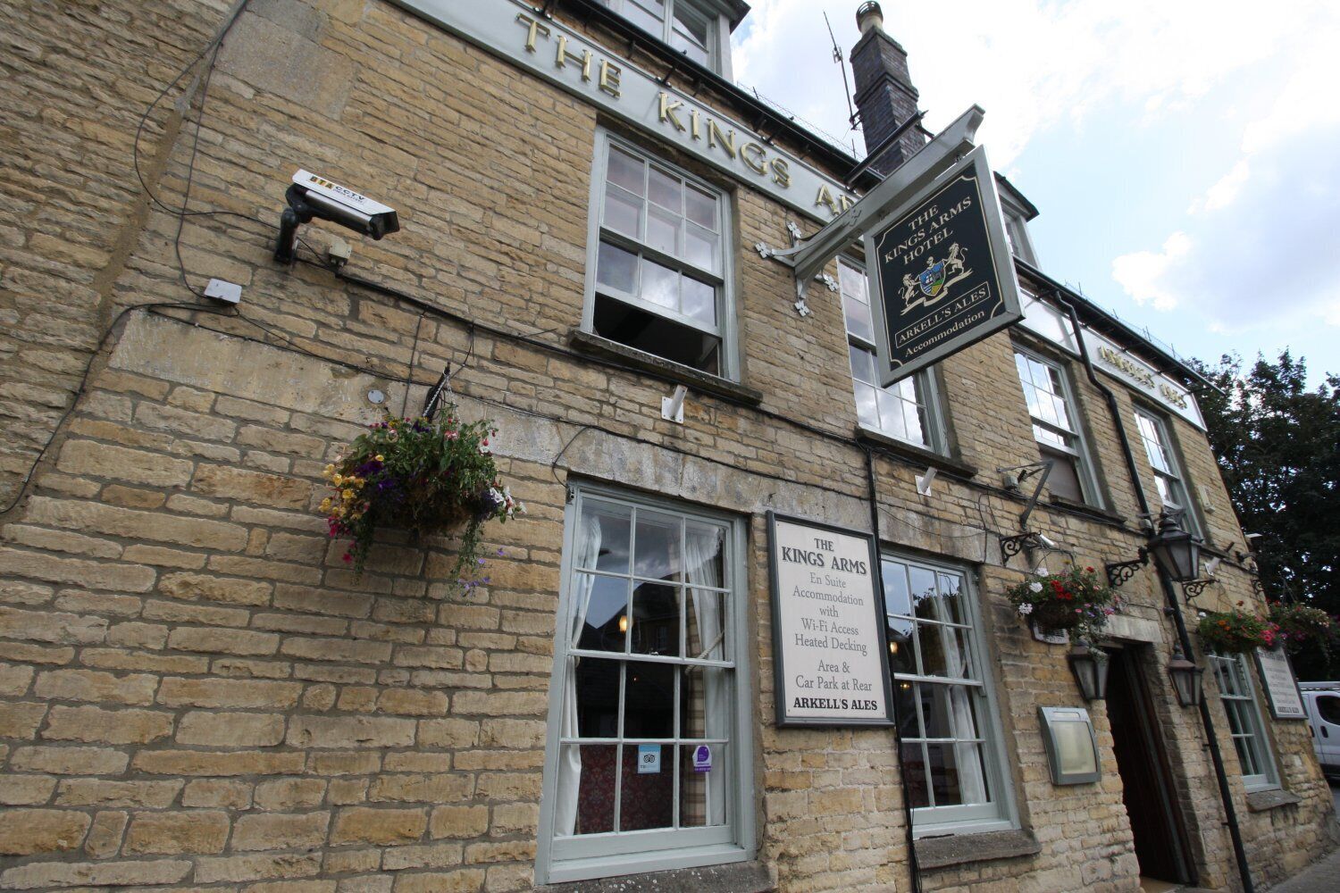 A traditional stone building with signs for 'The Kings Arms Hotel' and 'ARKELL'S ALES'.