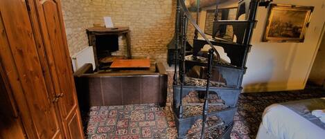 A room with a spiral staircase, a wooden cabinet, a small table with a book, and a patterned carpet.