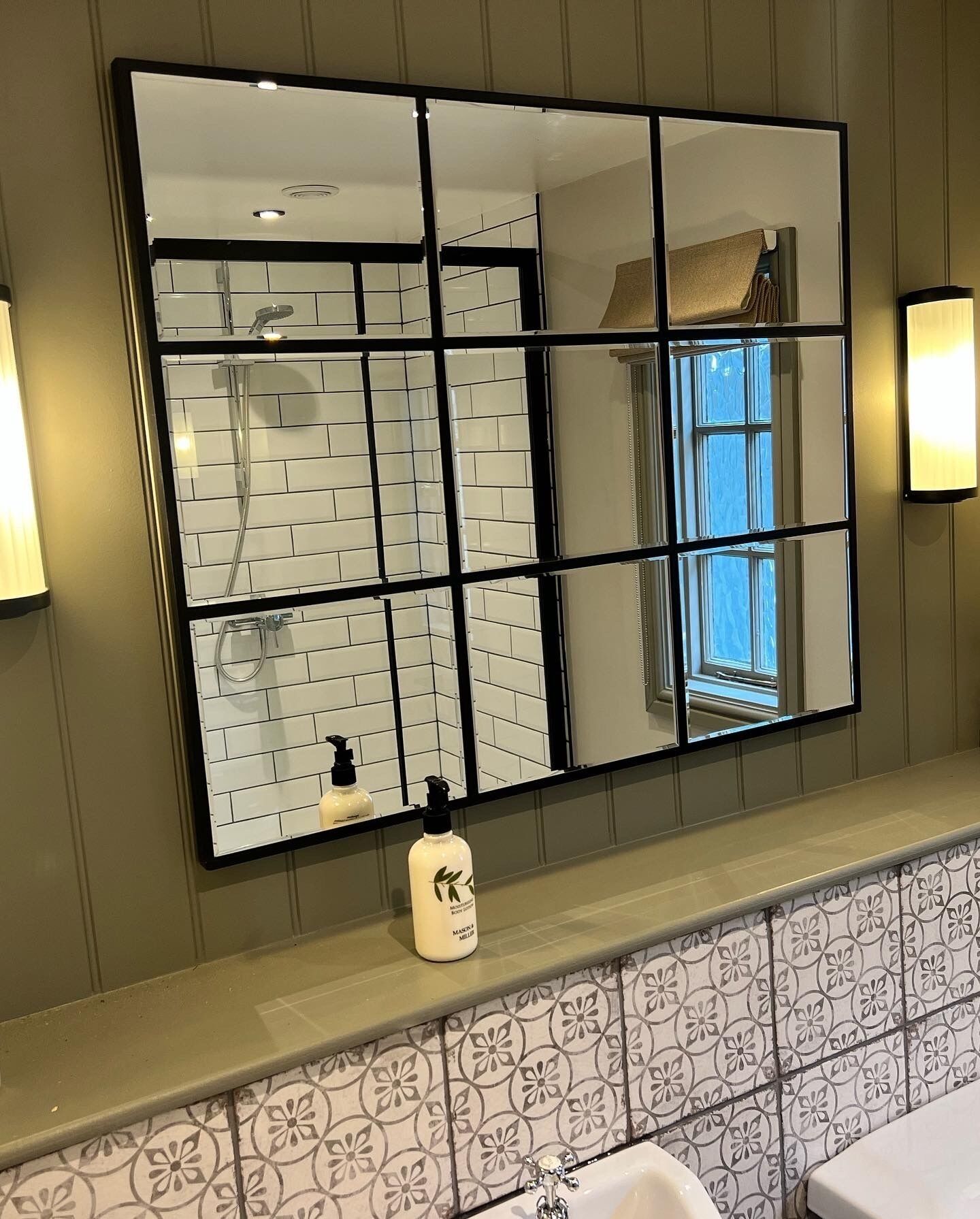 A bathroom with a large mirror, a toilet, and a sink.