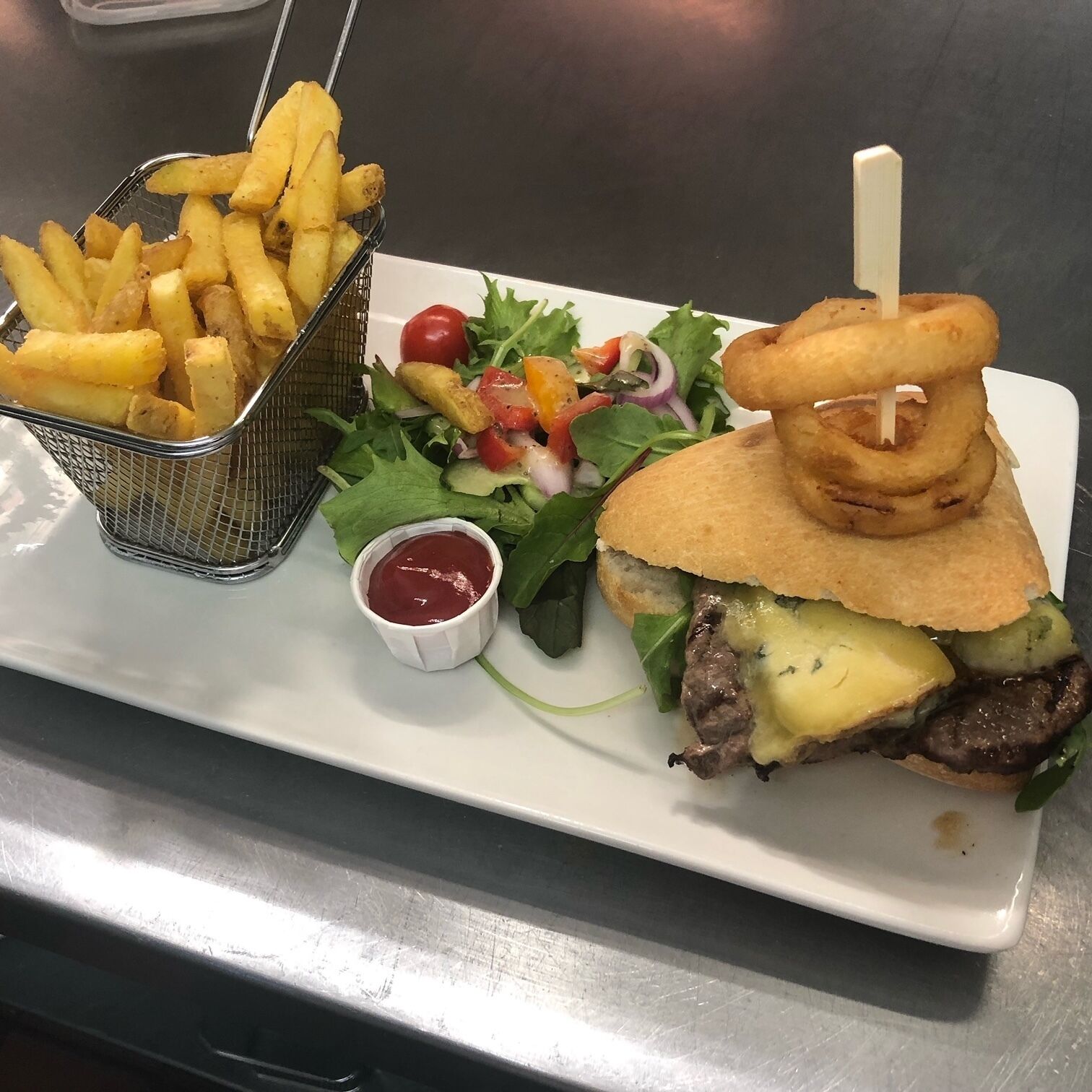 Une assiette avec un hamburger, des frites et une salade.