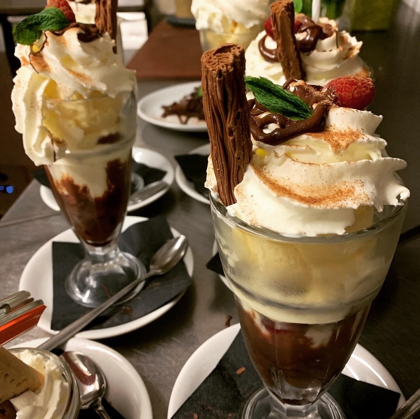A dessert with whipped cream, chocolate, and mint leaves.