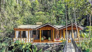 A wooden cabin with a porch and a small pool, surrounded by lush greenery. - Pacuare Lodge by Böëna (Siquirres)