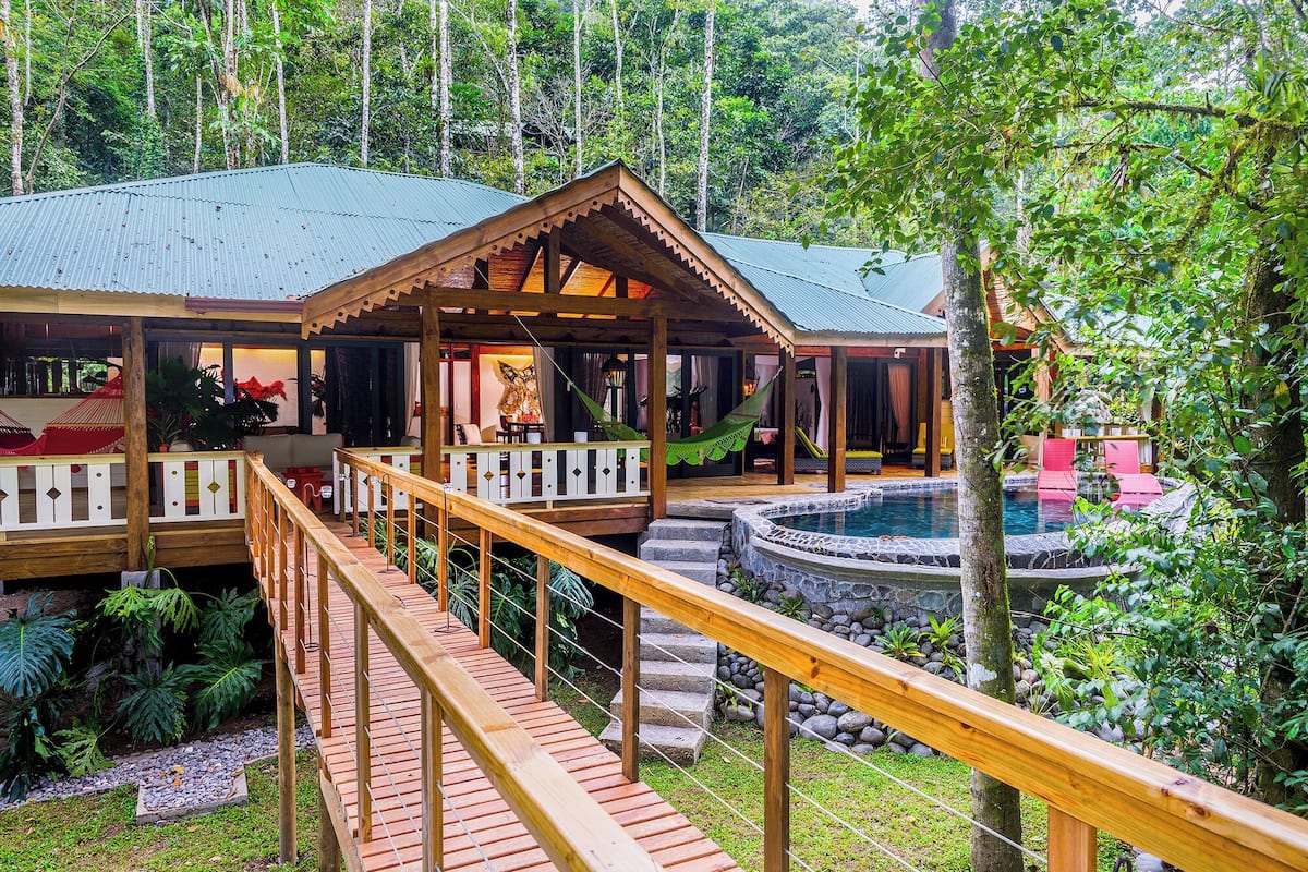 A wooden structure with a pool, surrounded by lush greenery.