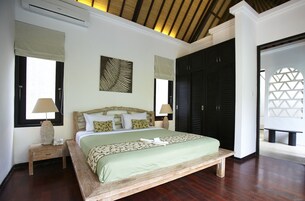 Un'ampia camera da letto con un letto grande, una testiera in legno e una ventola a soffitto.