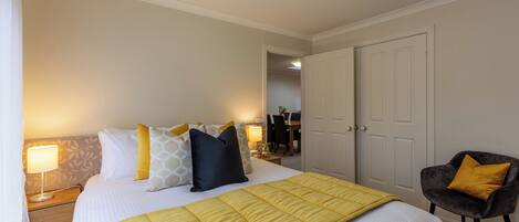 A hotel room with a bed, bedside tables, a chair, and a door.