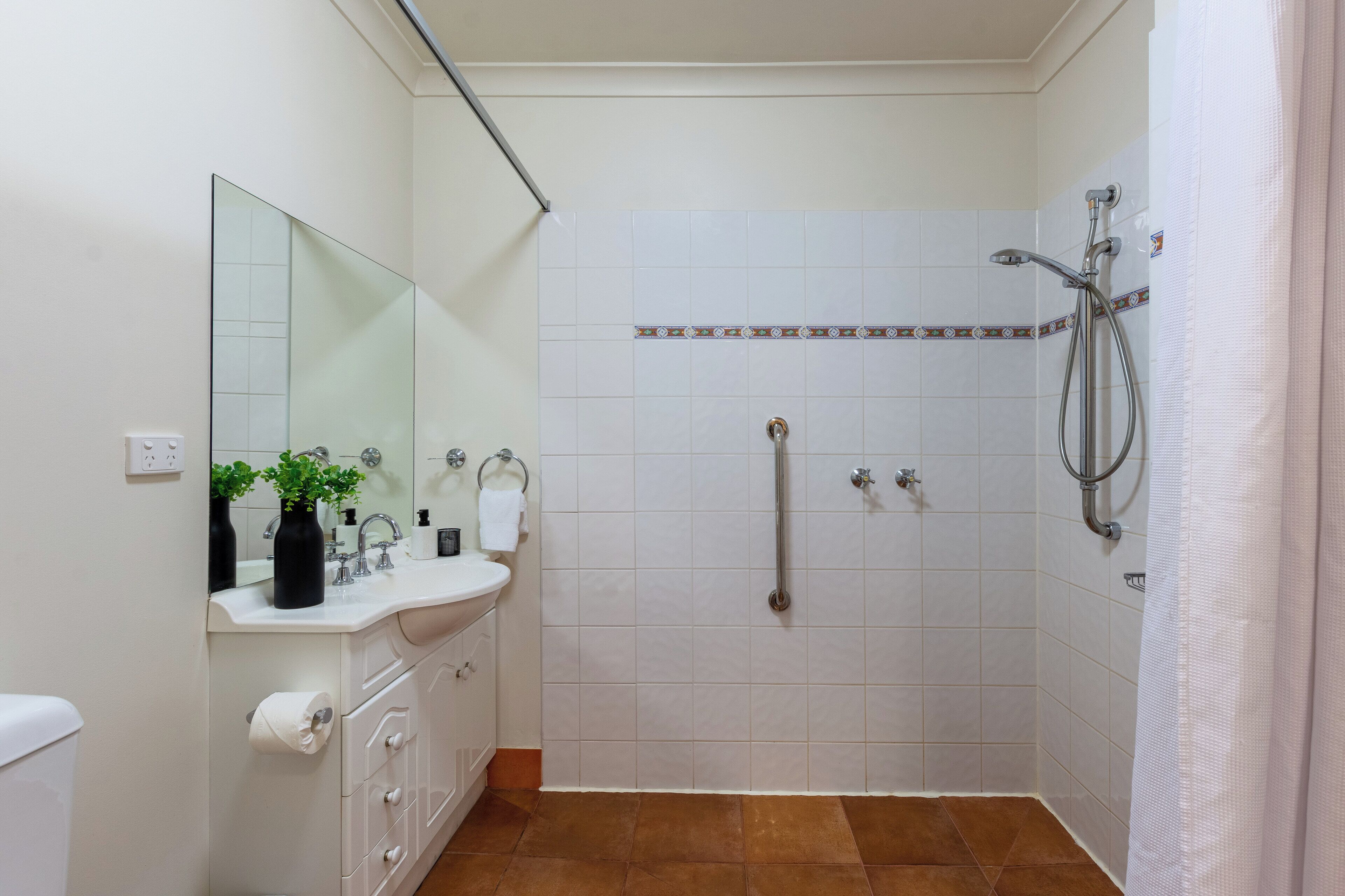 Une salle de bain avec un lavabo blanc, un miroir et une douche.