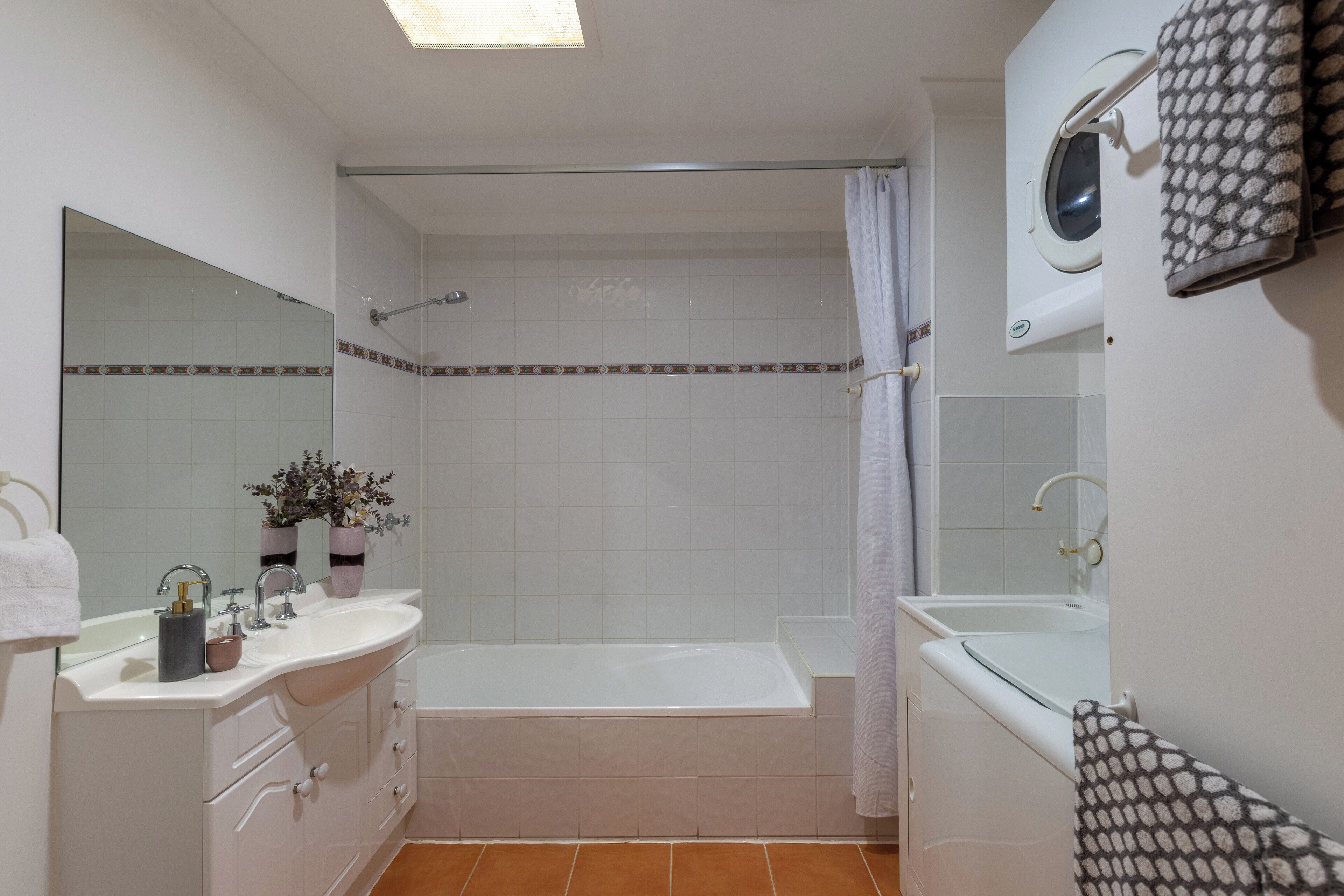 A bathroom with a bathtub, a sink, a mirror, and a shower curtain.